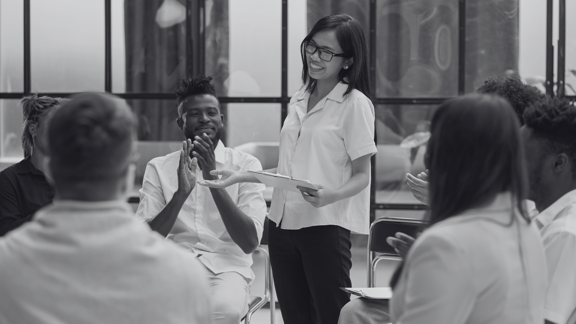 Woman presents to a circle of colleagues