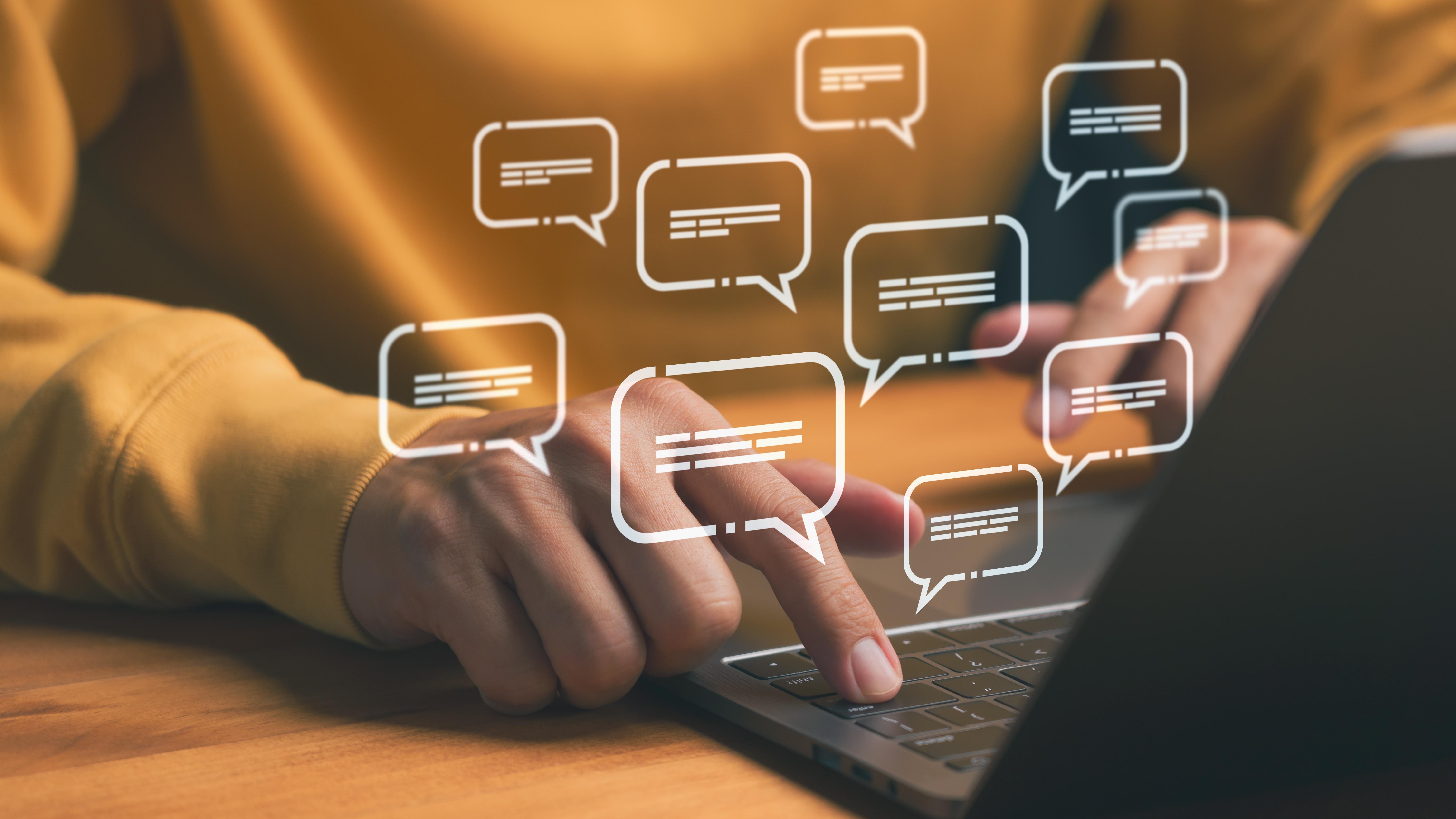 Hands typing on laptop with digital message icons, representing chat messages on Zoom