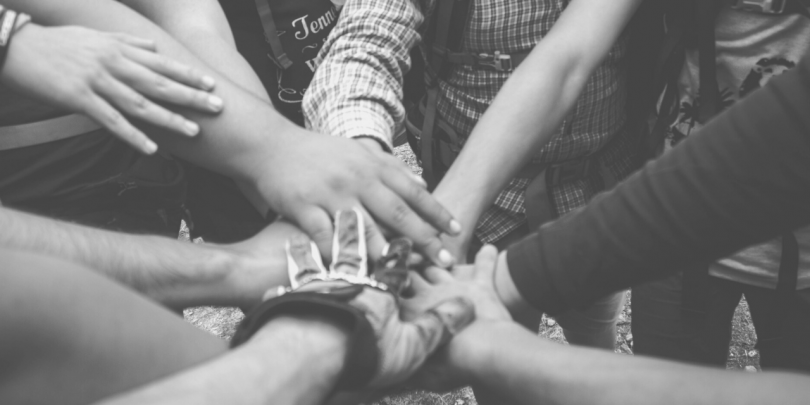 black and white image of hands coming together in a huddle