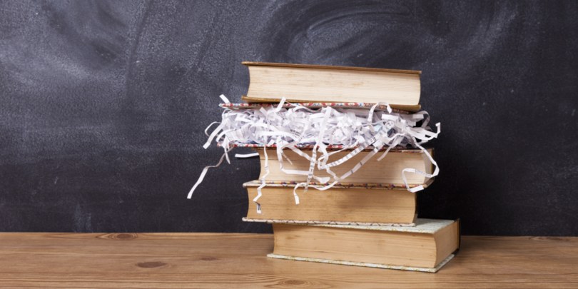Stack of books with one book full of paper shreds