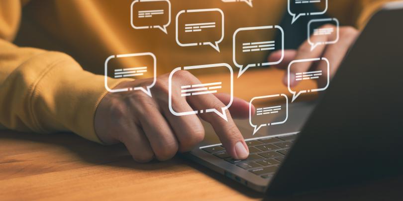 Hands typing on laptop with digital message icons, representing chat messages on Zoom