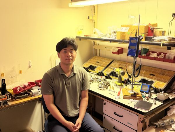 Man sits in front of workbench with hydrological equipment.