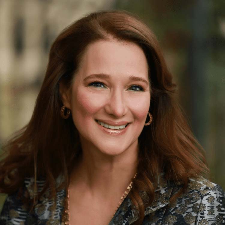 Headshot of Amy Werner Chronis wearing gold hoop earings and a gold necklace.