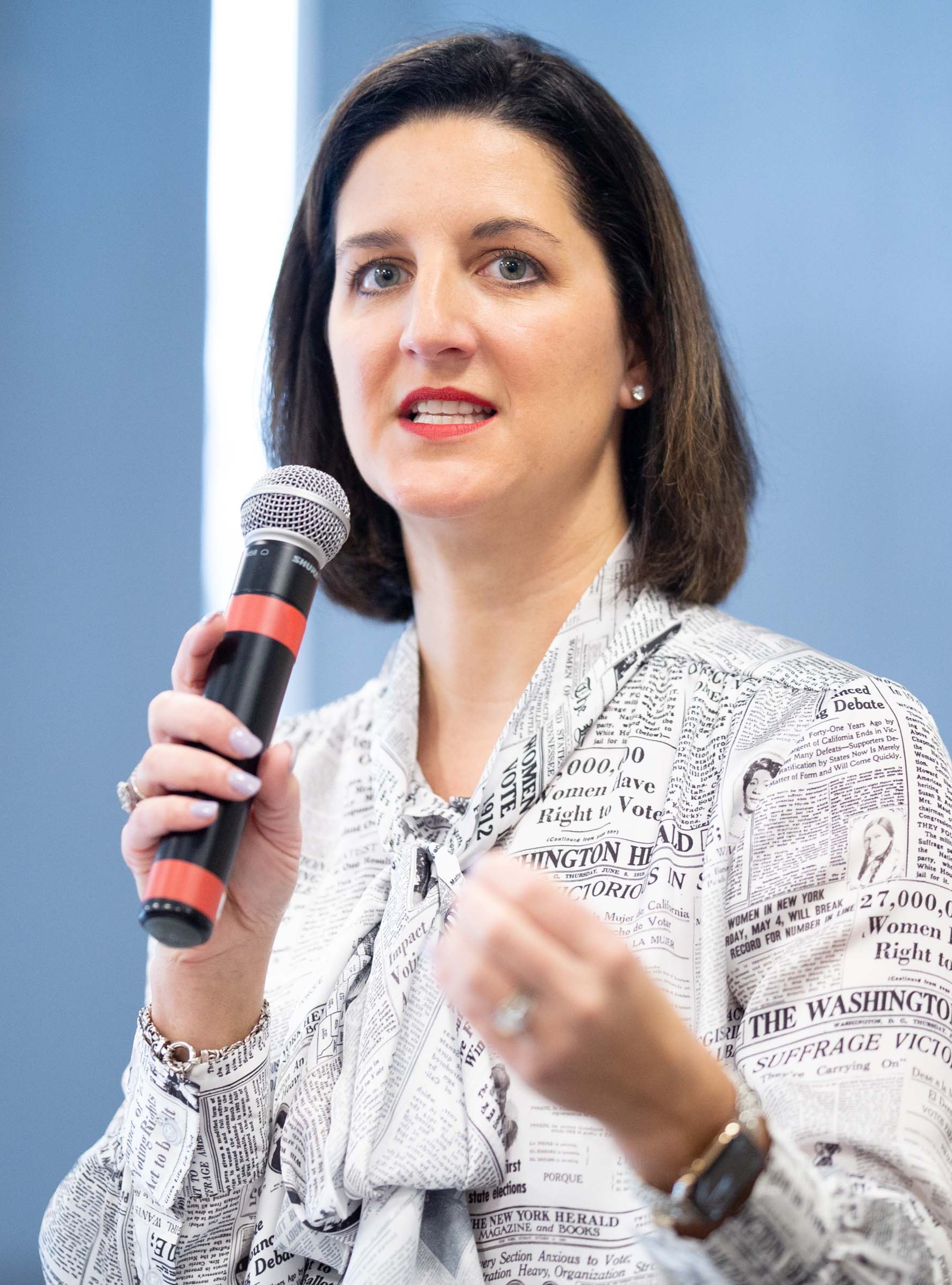 Nicole Balkenbusch holding a microphone and speaking.