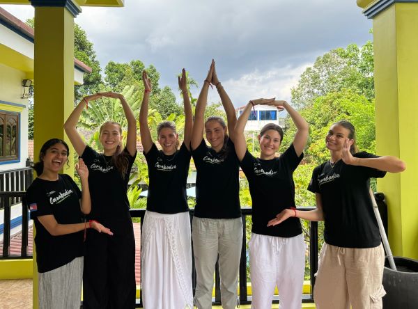 Six students dressed in black t-shirts with the words Cambodia spell out O-H-I-O on a hotel balcony