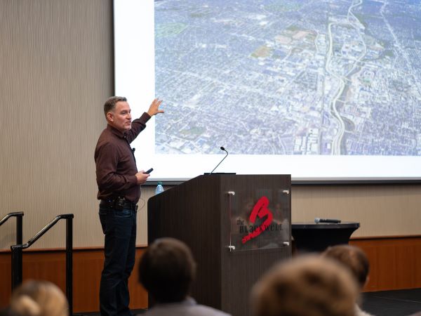 Chris points to a Google aerial view showing Columbus and Ohio State that is projected on a screen