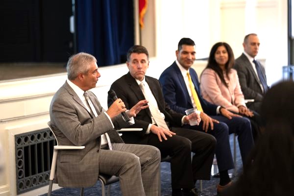 Five individuals sitting in front of room in chairs