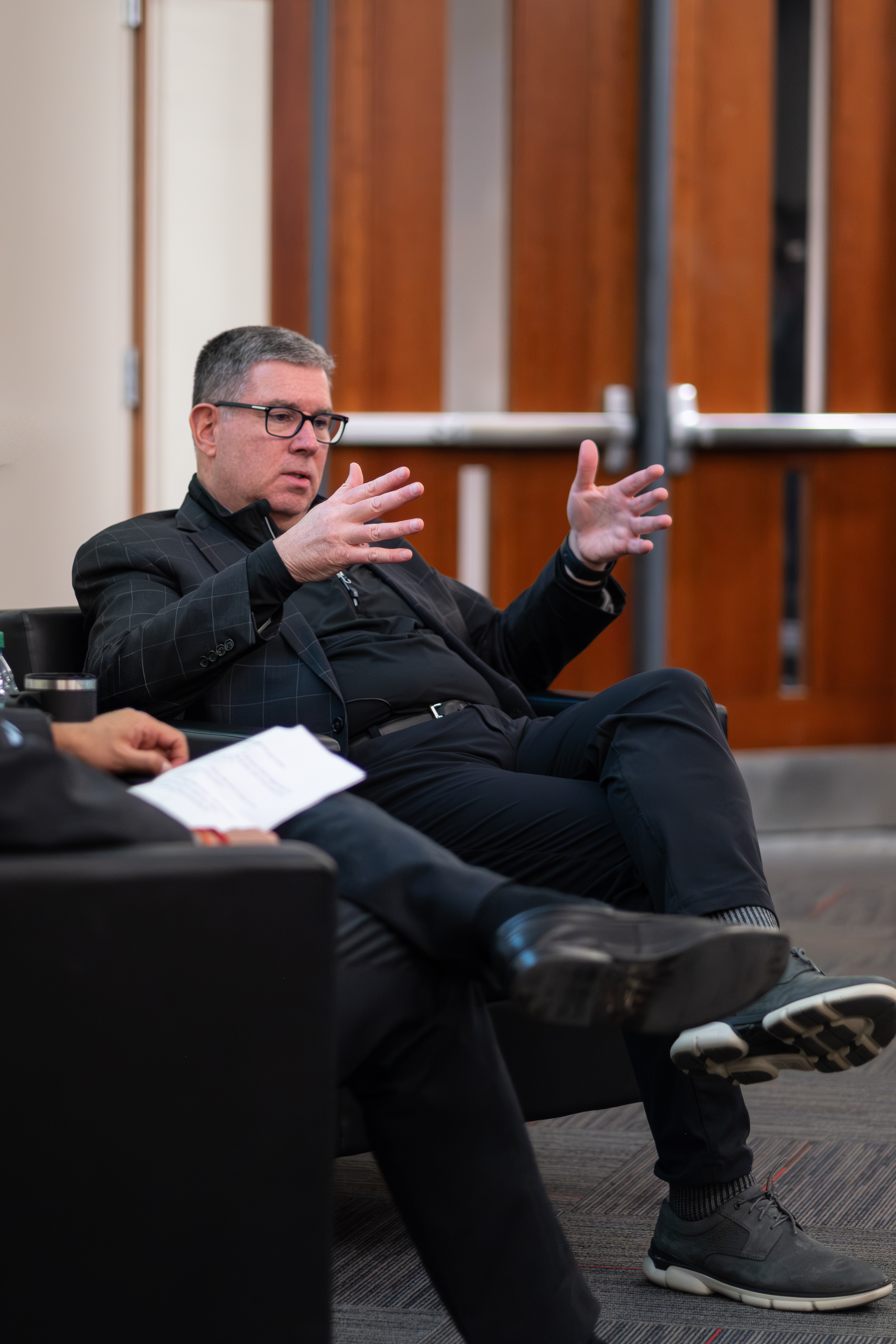 Man in business attire sits in chair with legs crossed