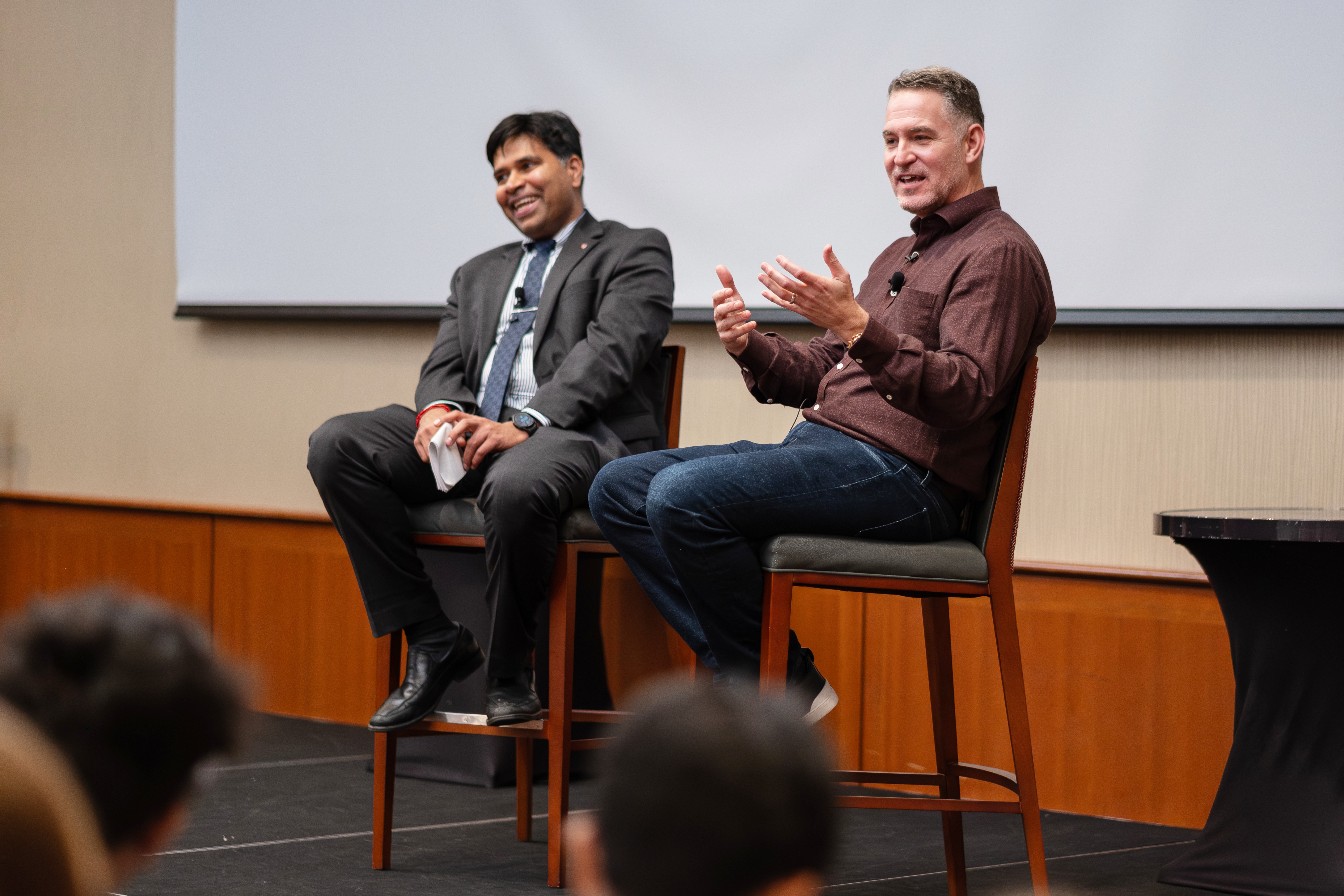 Two men sitting on high rise chairs on platform