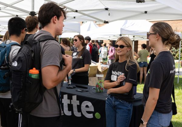 students interacting with two employees dressed in Deloitte t-shirts