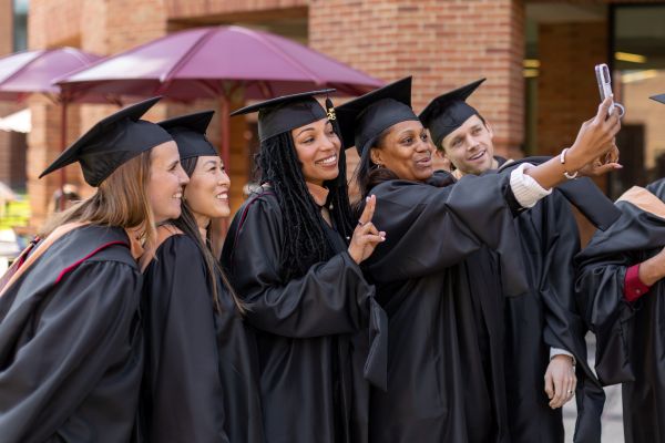 Group of students in cap and gown take a selfie together