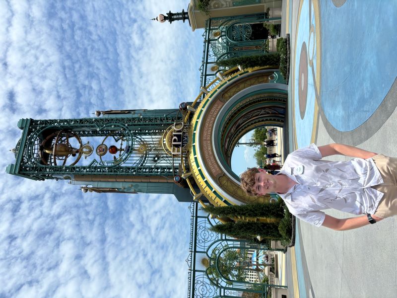 Tyler DiFranco poses in front of a three story, grand entrance at the park