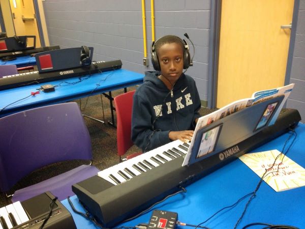 Lee wearing a Nike sweatshirt wearing headphones while sitting in front of a keyboard