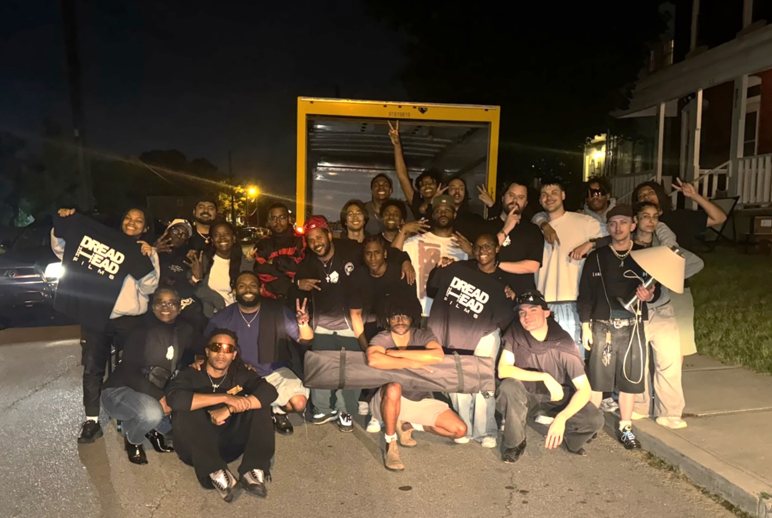Group photo of the production crew posing on the street in front of an moving truck.