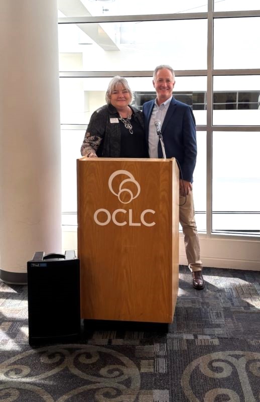 Woman and man behind podium that says OCLC