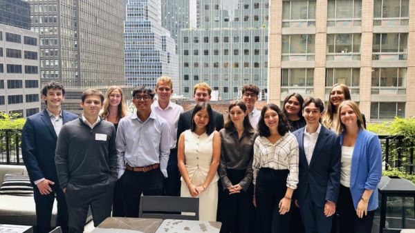 Group of 14 people gathered on patio with high rise buildings in background