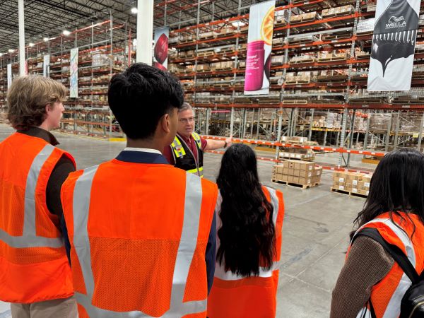 Students in orange vests inside a warehouse