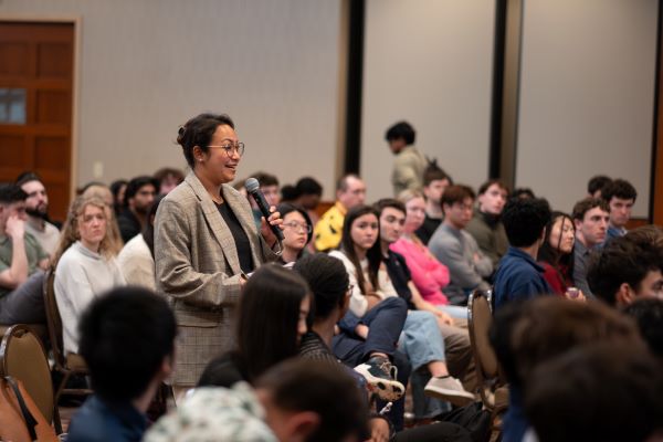 Student holding microphone in room filled with other students