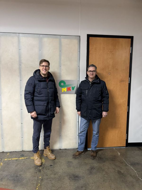 Two men in winter coats standing inside an office by front door