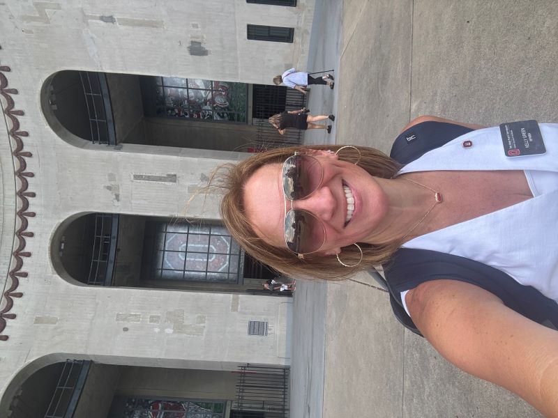 Woman with white shirt, backpack and sunglasses in front of the entrance to Ohio Stadium
