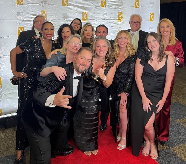 Group of men and women dressed up holding and Emmy