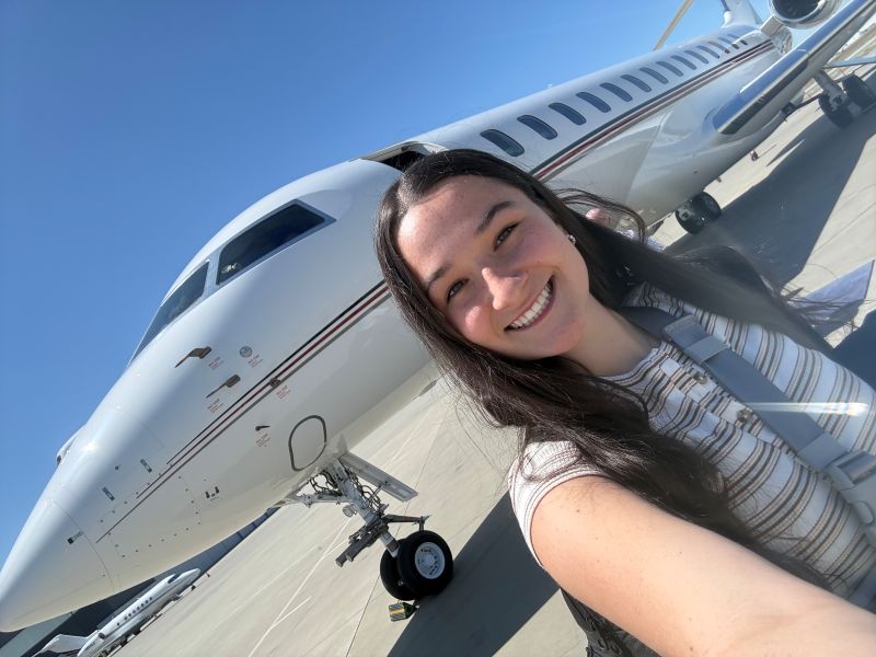 Picture on an angle of woman taking selfie in front of small jet
