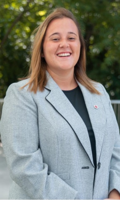 Nicole Mazullo in a light gray blazer with an Ohio State pin poses outside for her homecoming portrait.