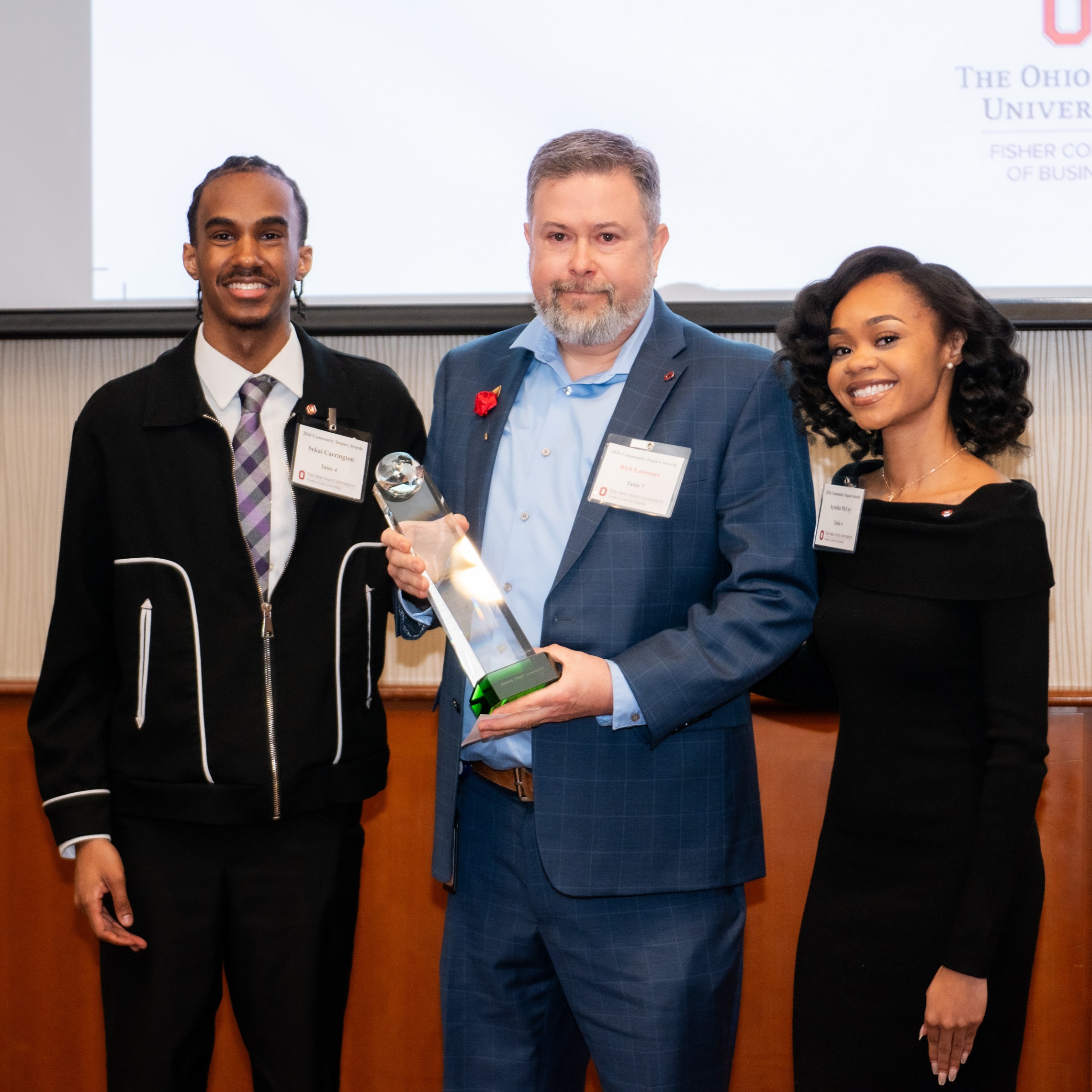 Students Sekai Carrington, left, and Ayeisha McCoy, far right, pose with Rich Lawrence, center, who is holding his Community Impact Award.
