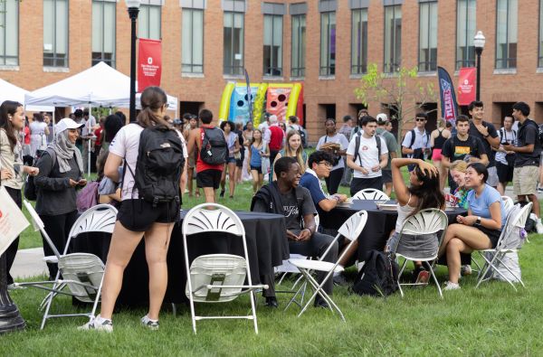 Group of students mingling on the quad and sitting at tables