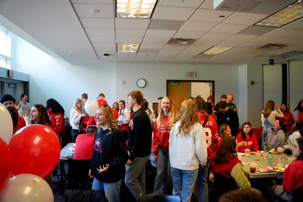 Students dressed in scarlet and gray milling around and enjoying tailgate food at the event.