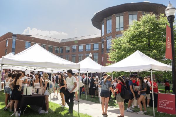 Group of tents set up on the quad with students visiting tables from various college departments
