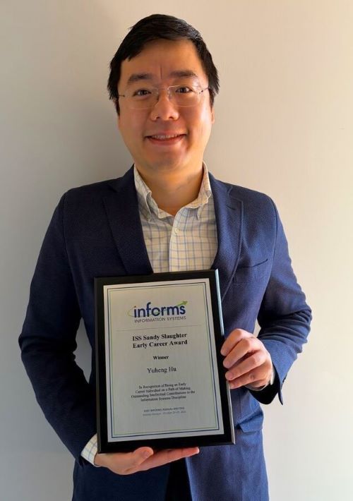 Yuheng Hu in white and blue plaid shirt with blue sport coat holding his informs award