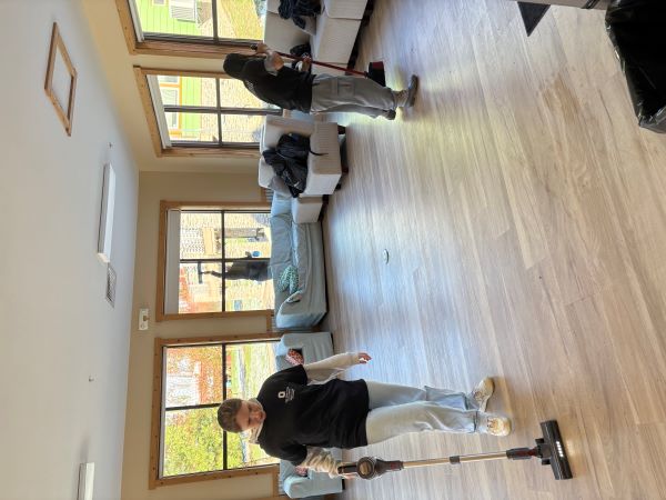 two students with vacuum and broom cleaning floors
