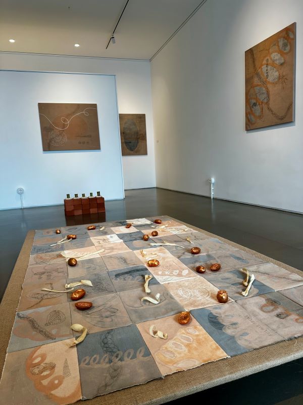 artwork in a plaid formation on the floor and paintings hanging on the wall