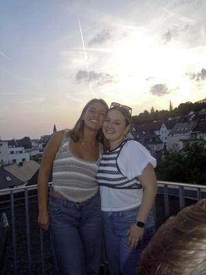 Caitlyn Walrod and a friend pose in front of a sunset in Europe.