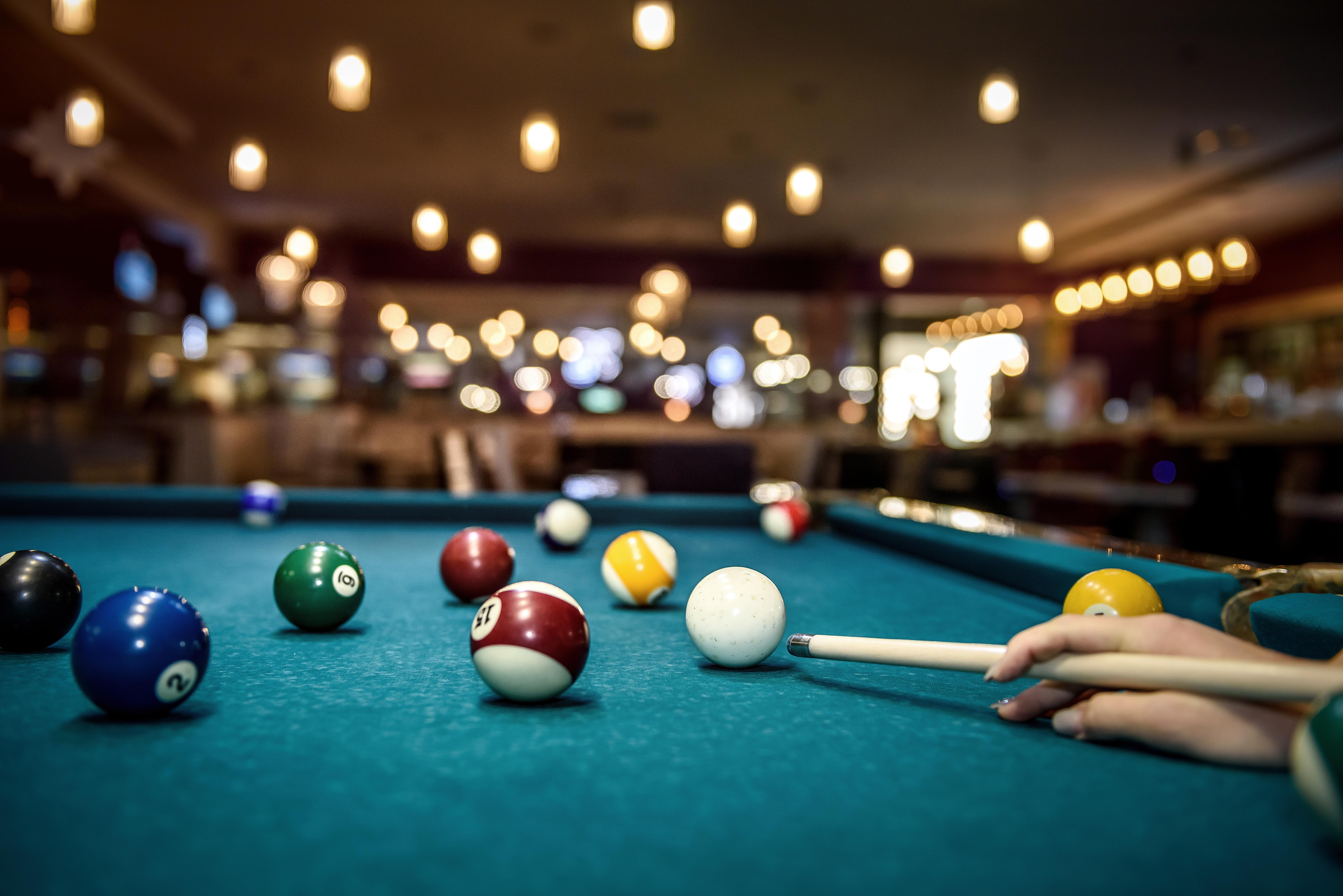 Hand on cue stick ready to strike the cue ball on a billiards tablel