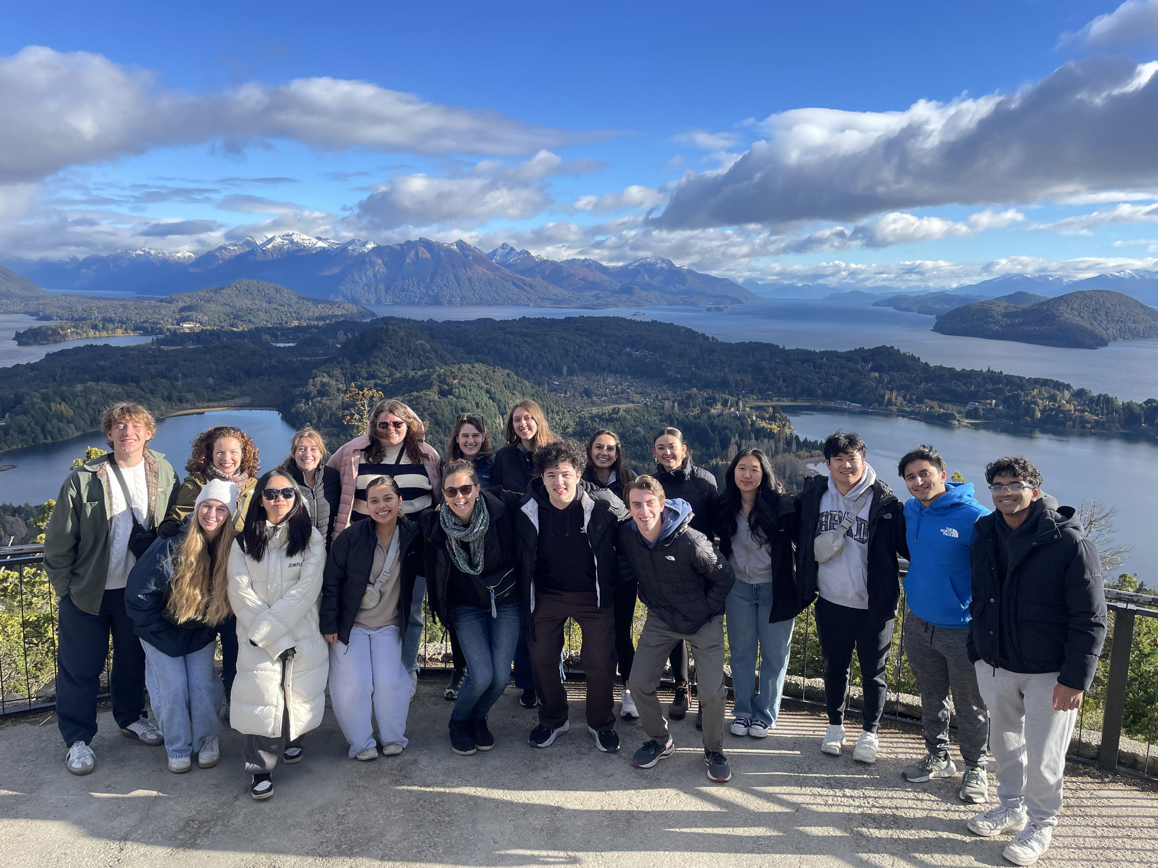 Group of students pose on platform with water and mountains in the background in Argentina.