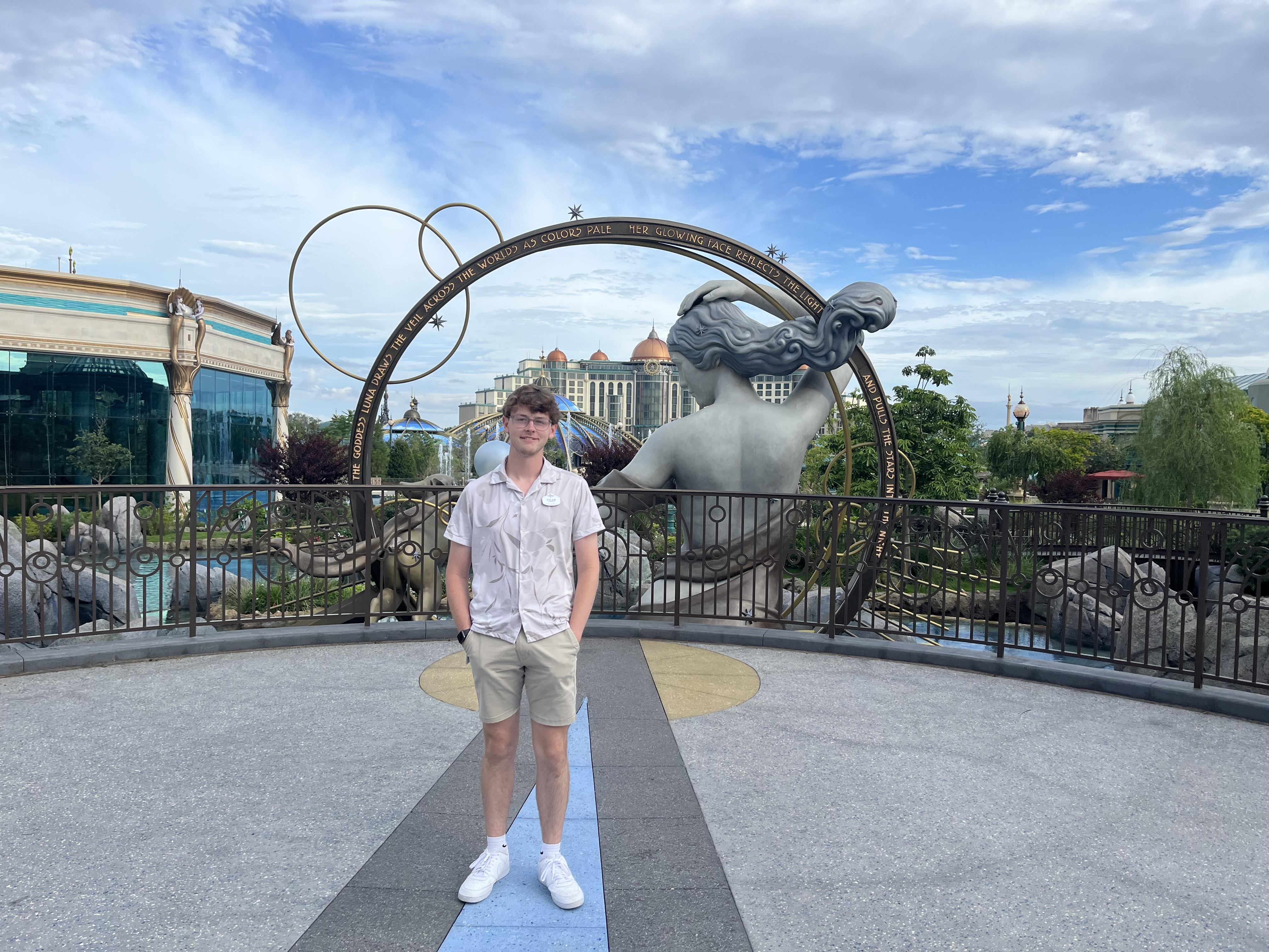 Tyler DiFranco in shorts with oversized sculpture of person with flowing hair and arch in the Court of the Moon in Celestial Park
