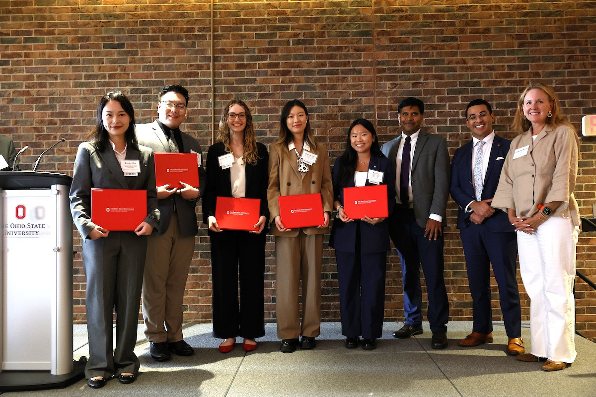 Ohio State students, Fisher Interim Dean Aravind Chandrasekaran, Dominic DiCamillo, CIBER, and Roberta Winch, Columbus State, pose for a photo in front of a brick wall.