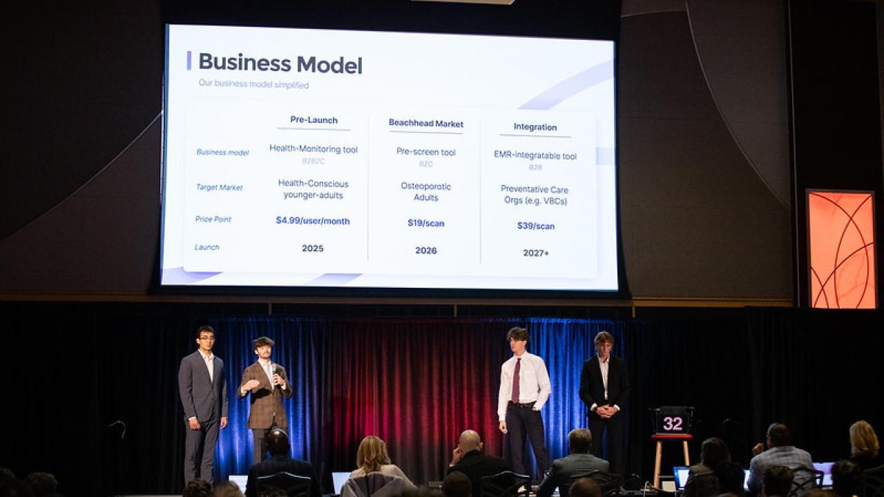 Students on stage giving presentation with screen over their heads