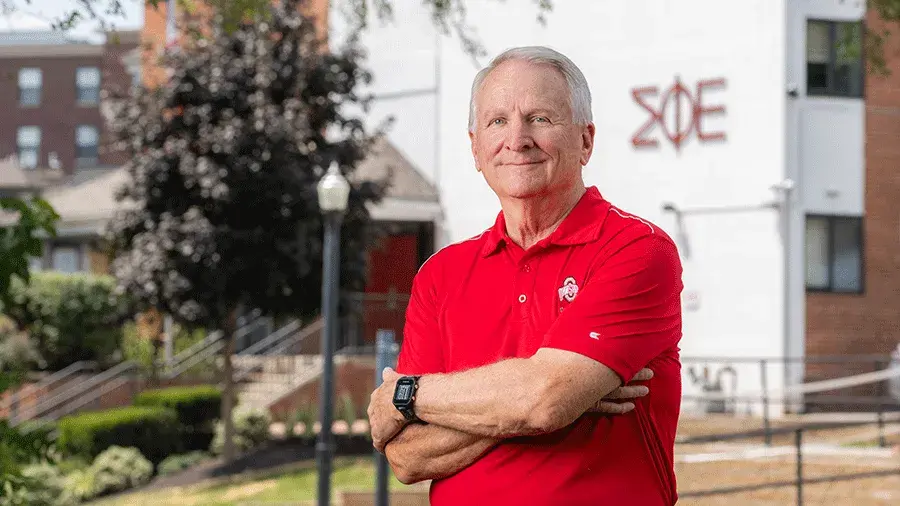 John Wagner poses in a scarlet Ohio State shirt outside of his former fraternity house.
