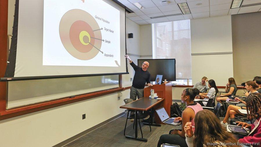 Jeff Dotson gestures to a projector screen in a classroom.