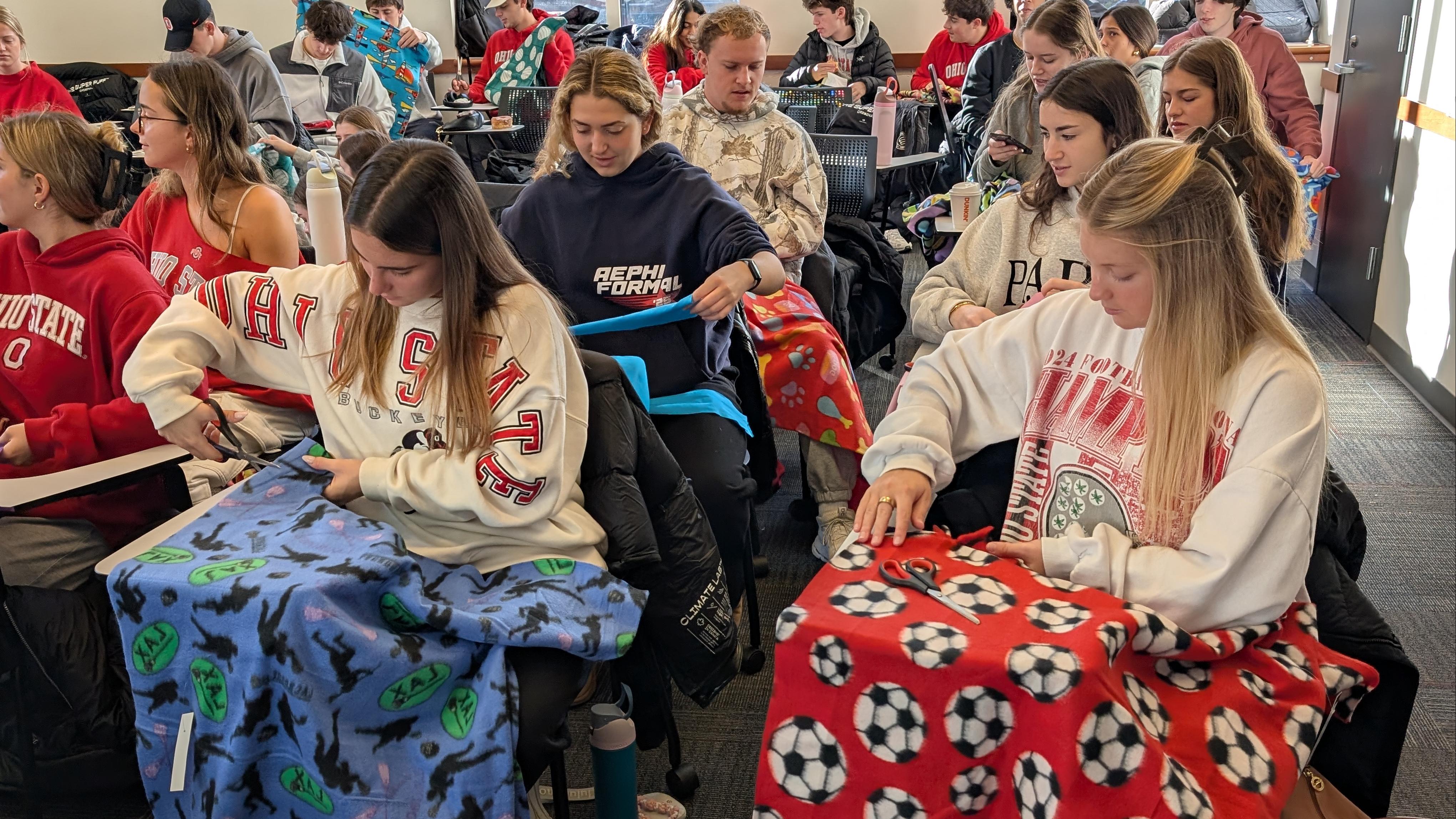 Group of students creating no sew flannel fleece blankets