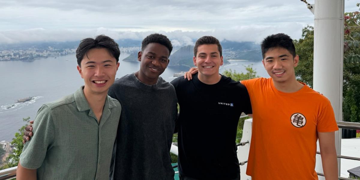 Four male students with arms around each other's shoulders