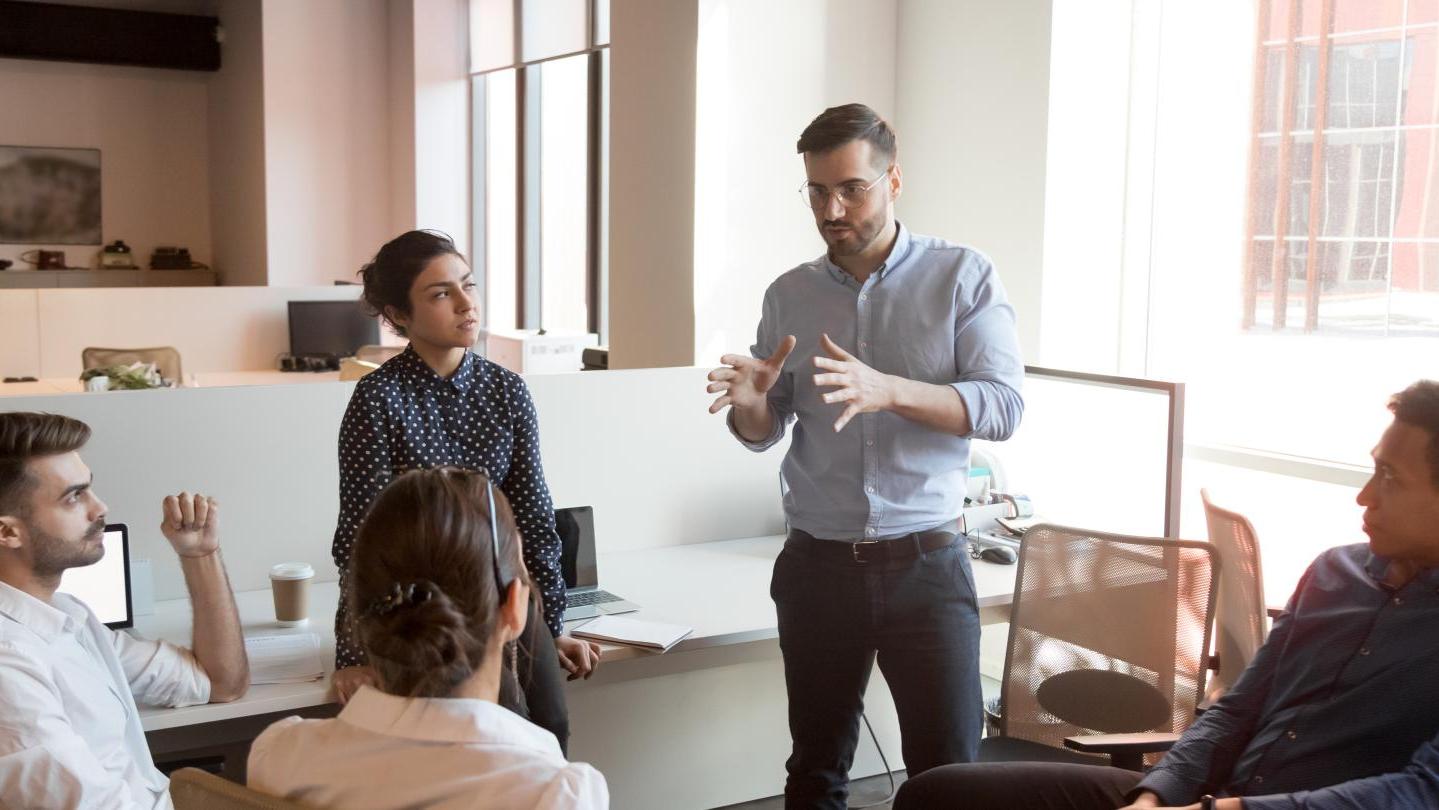 Group of people sitting and listening to someone standing and talking