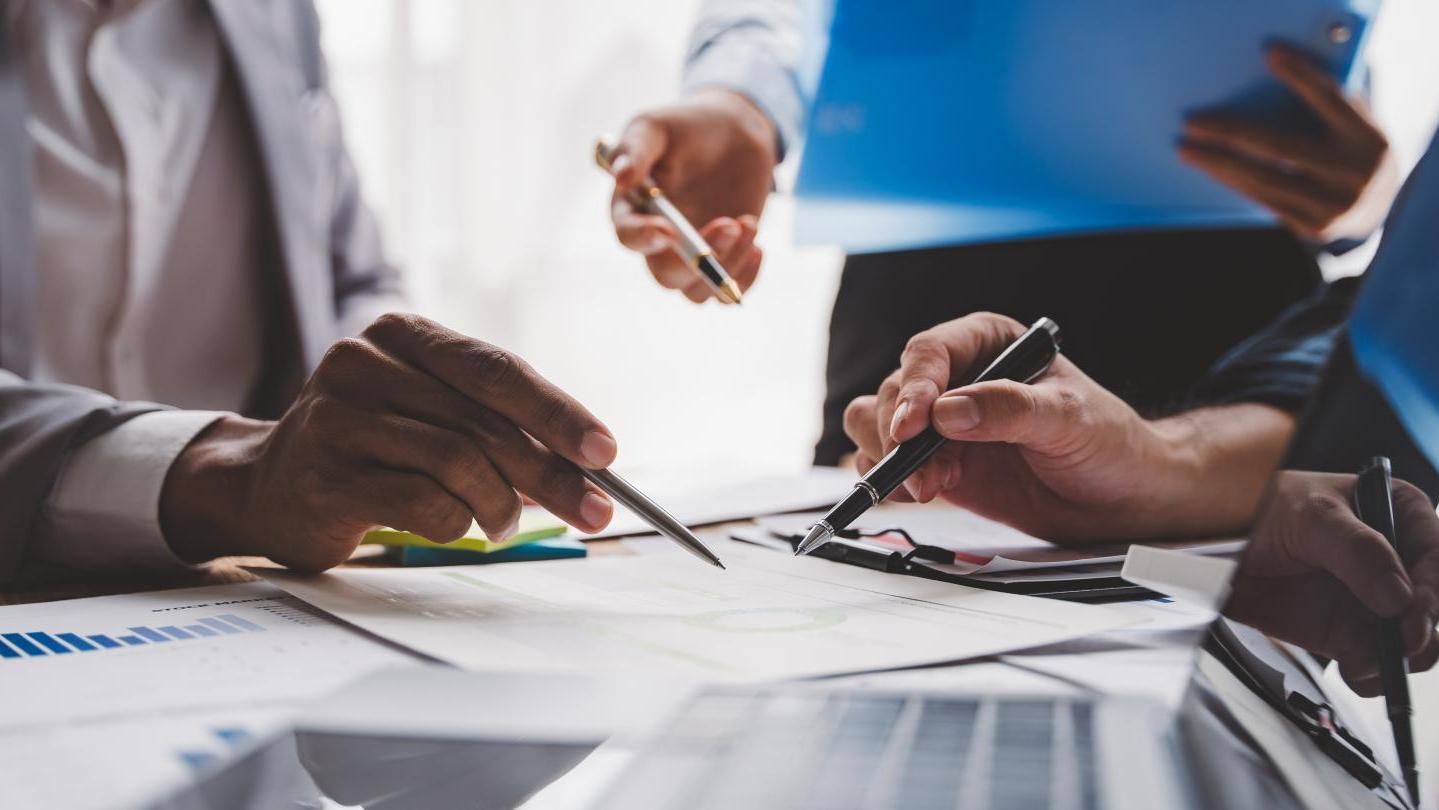 close up of hands at a desk with a computer and paperwork