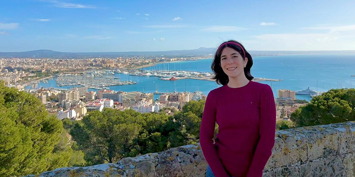 Catie Russ poses on a mountain side with bay behind her.