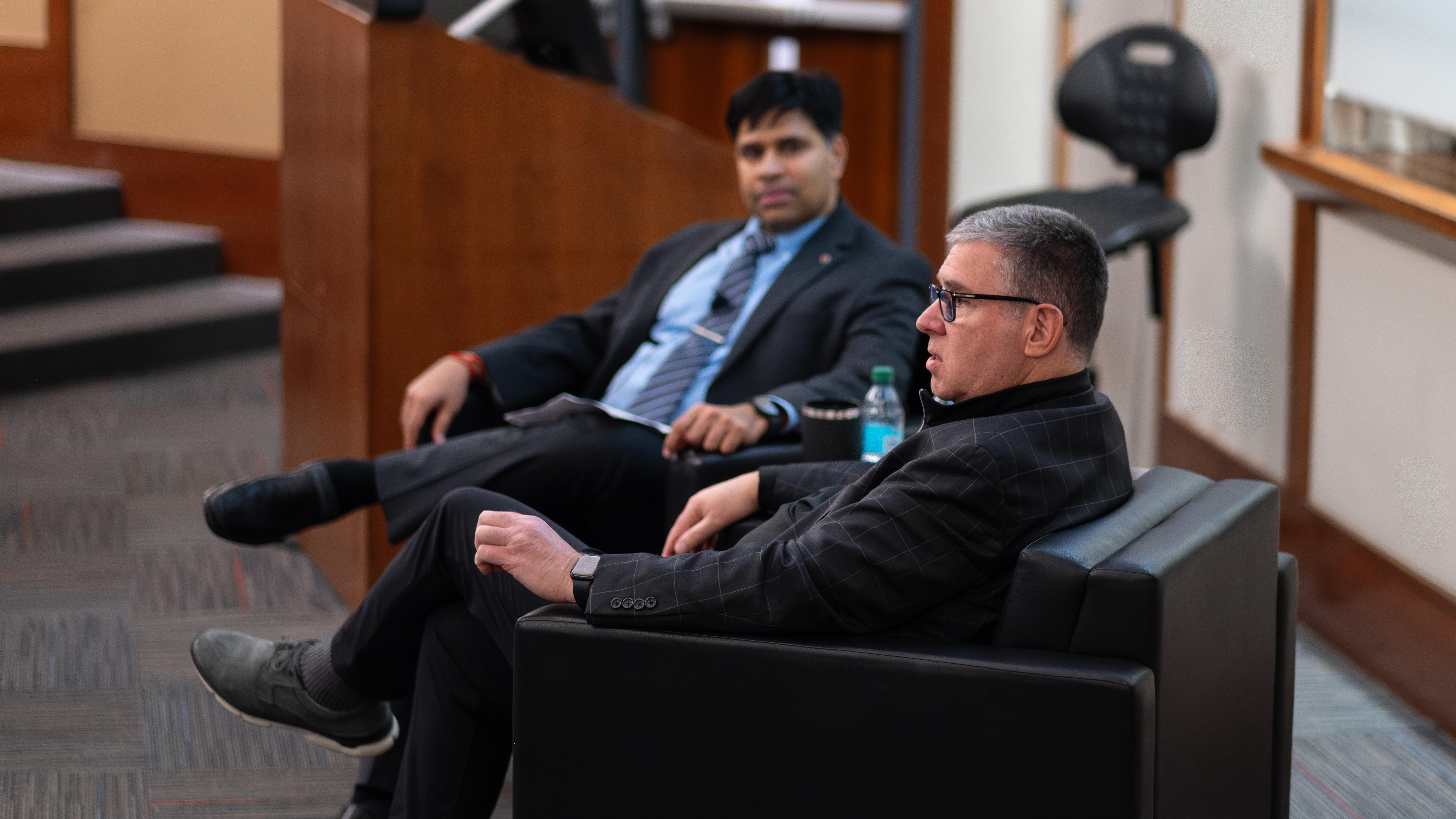 Interim Dean Aravind Chandrasekaran and James Kavanaugh sitting in chairs in front of classroom