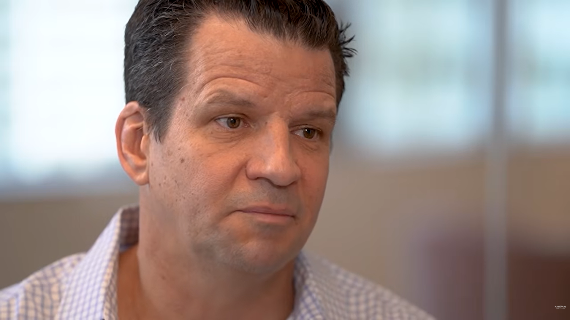 John Gray in a white collard shirt talks to an off-camera reporter.