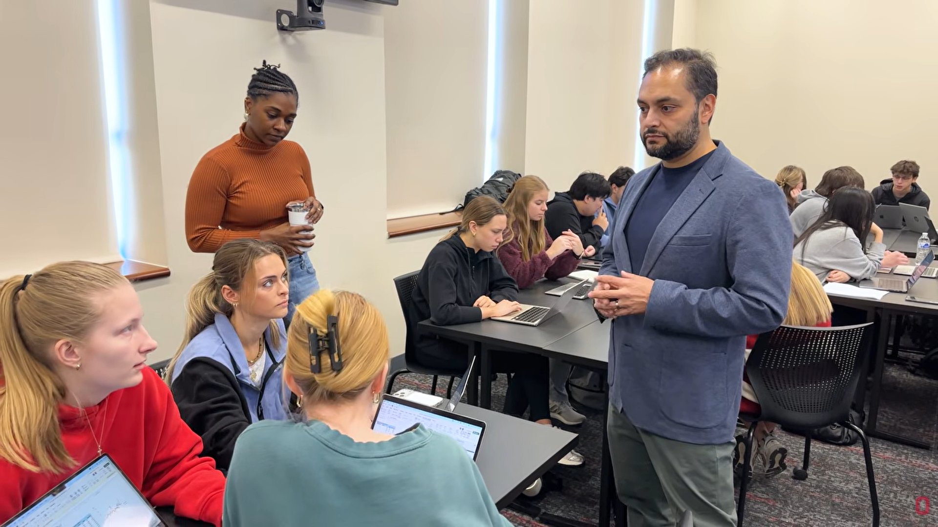 Vince Castillo speaks with students working on laptops in a classroom discussion.